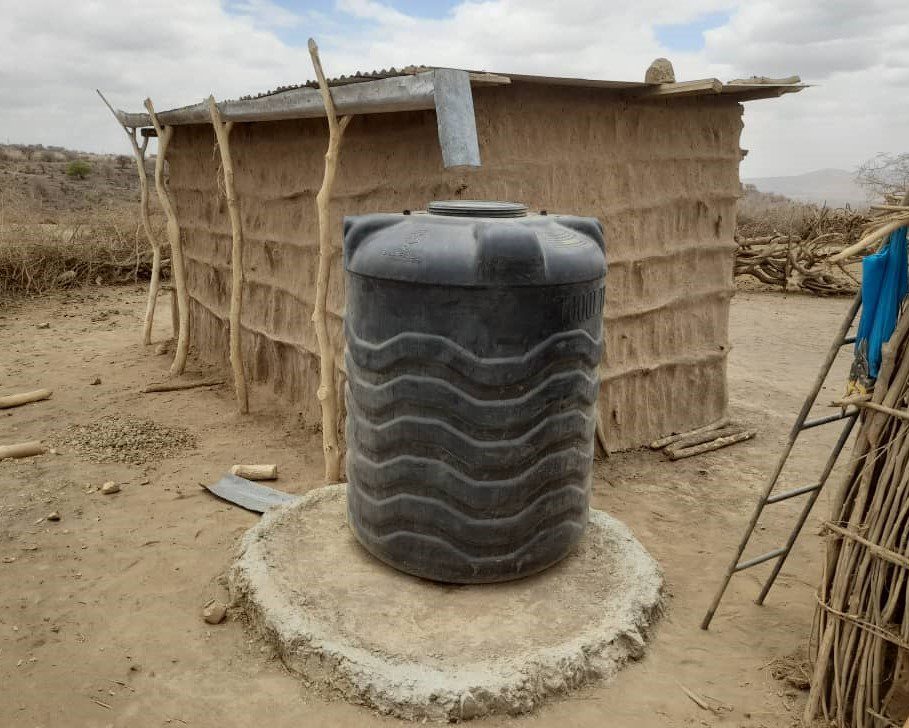 Metal roof and gutters on rectangular mud structure with 1,000-liter water tank